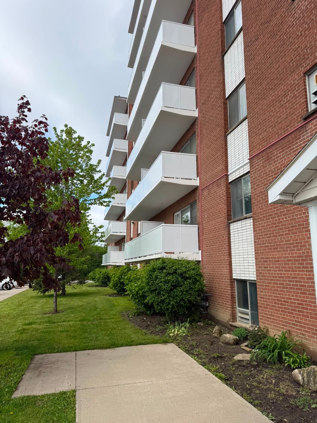 Balconies on a red-brick building after repair, each with new white panel guards