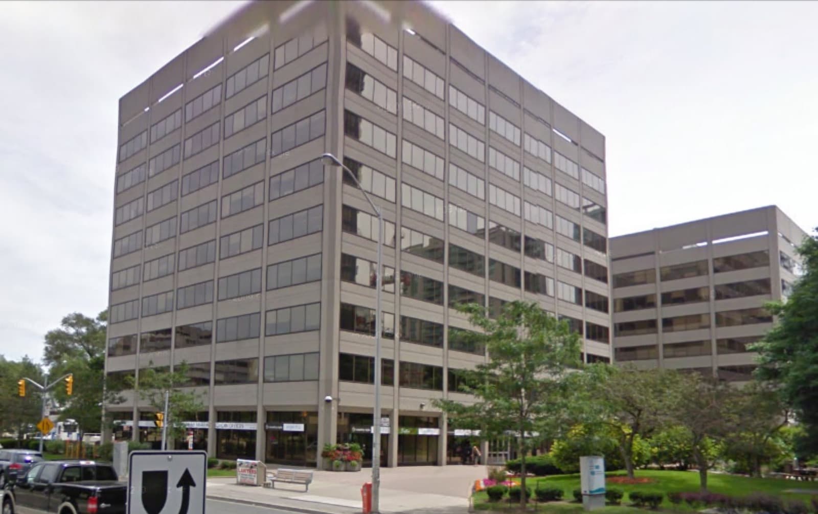 A multi-storey office building with a landscaped plaza at a street corner
